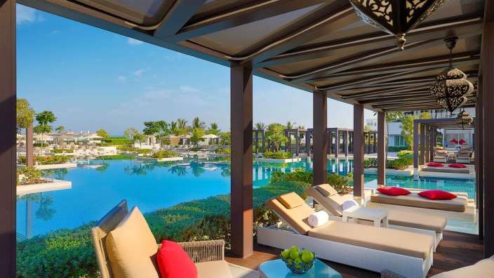 Eine Terrasse mit Liegestühlen und Stühlen mit Blick auf einen großen Pool