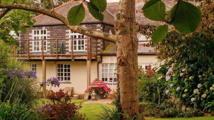Ein Haus mit einem Balkon und einem Baum im Vordergrund