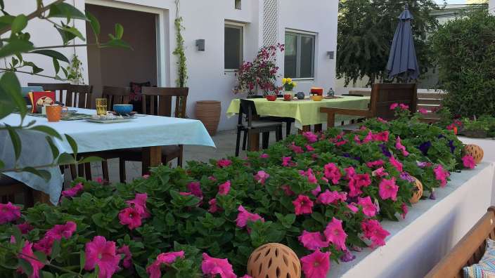 Ein Tisch und Stühle auf einer Terrasse mit rosa Blumen