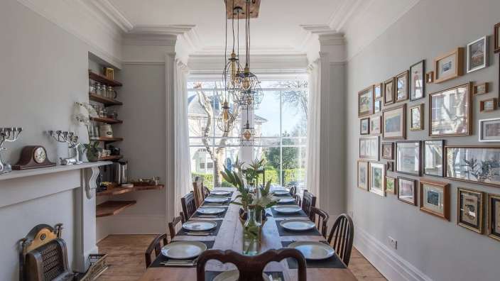 Ein Esszimmer mit einem Tisch und Stühlen und Bildern an der Wand