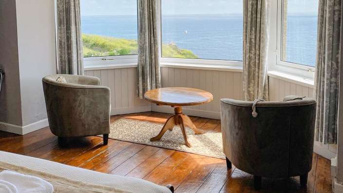 Ein Zimmer mit zwei Stühlen und einem Tisch mit Blick auf das Meer