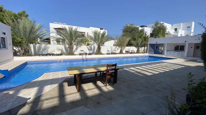 Ein Tisch und Stühle stehen neben einem großen Swimmingpool