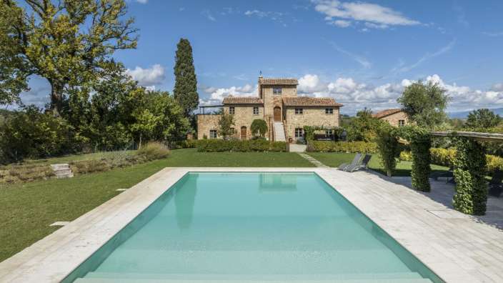 Ein großer Swimmingpool vor einem großen Steinhaus