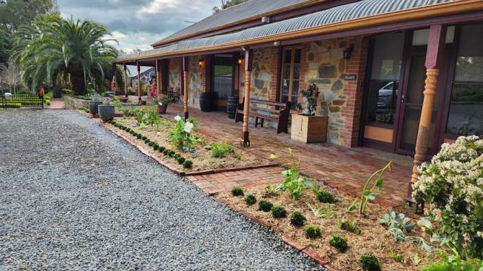 Ein großes Backsteinhaus mit einer Veranda und einem Garten davor