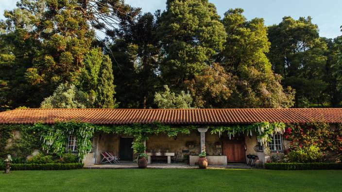 Ein Haus mit einem roten Dach und vielen Bäumen dahinter