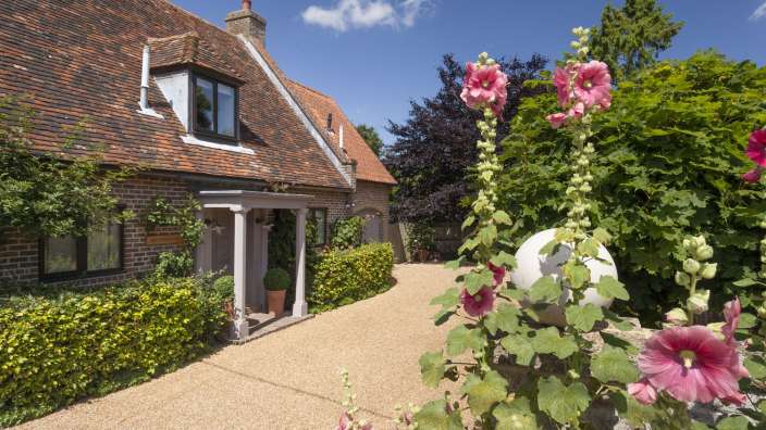 Eine Reihe rosa Blumen steht vor einem Backsteinhaus