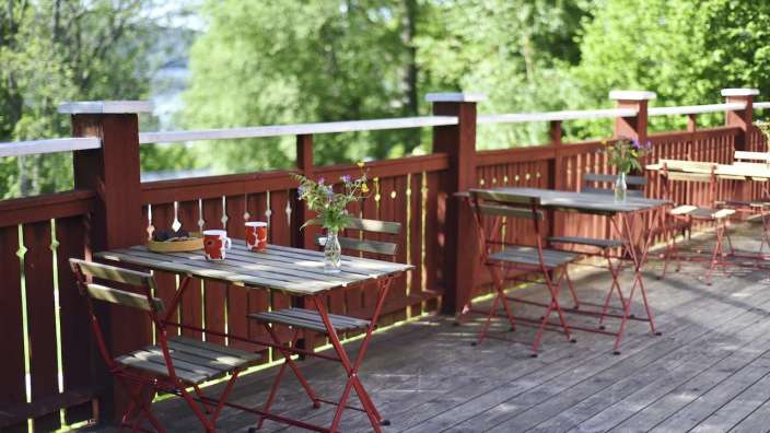 Ein Tisch und Stühle auf einem Holzdeck mit einer Vase mit Blumen darauf