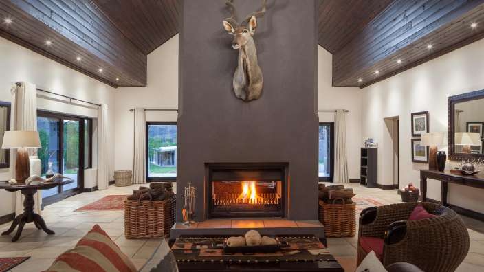 Ein Wohnzimmer mit einem Kamin und einem Hirschkopf an der Decke