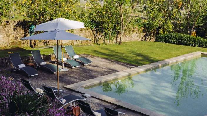 Ein Swimmingpool mit Liegestühlen und einem weißen Regenschirm