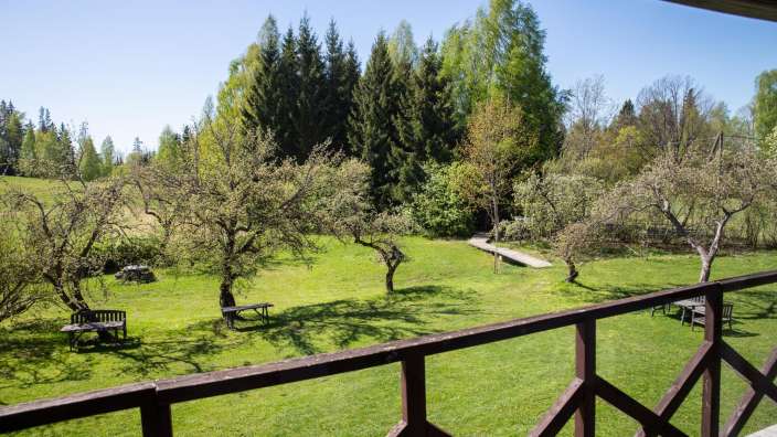 Ein Balkon mit Blick auf einen Garten mit Bäumen und Stühlen