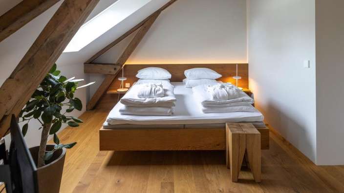 Ein Schlafzimmer mit einem Holzbett und einem Holzhocker