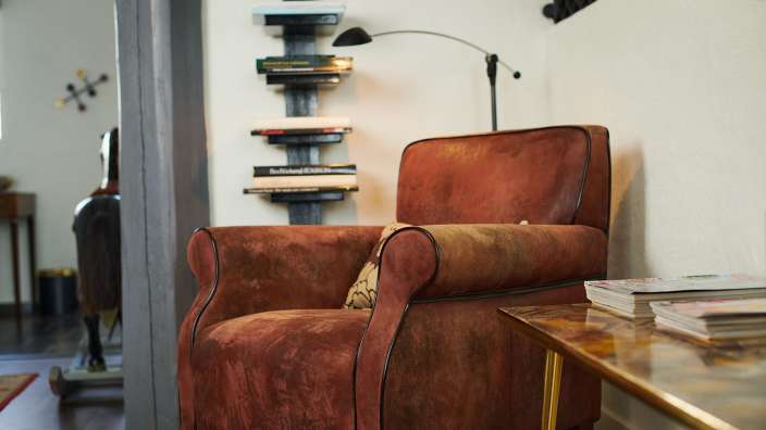 Ein brauner Stuhl sitzt neben einem Tisch und einem Bücherregal