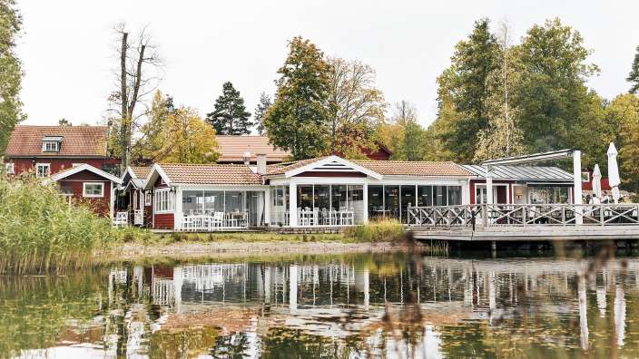 Ein rotes und weißes Haus steht neben einem Teich