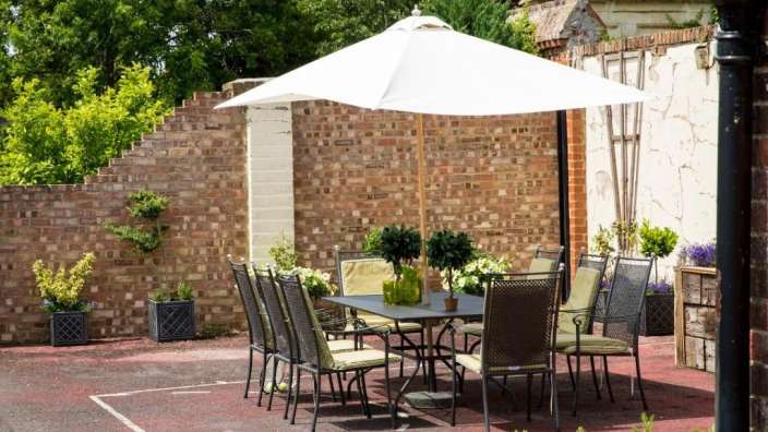 Ein Tisch und Stühle unter einem weißen Regenschirm vor einer Backsteinmauer
