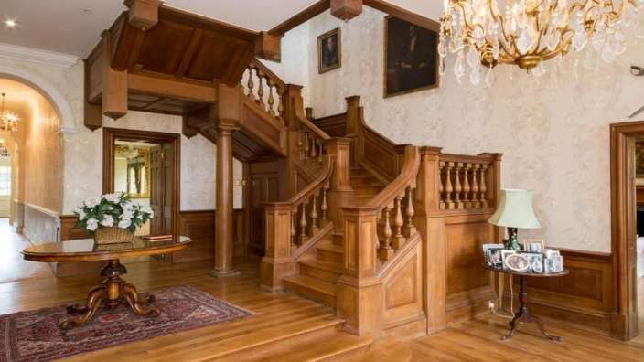 Ein Holztreppenhaus mit einem Tisch und einem Kronleuchter