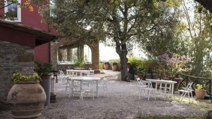 Eine Reihe von weißen Stühlen und Tischen in einem Garten