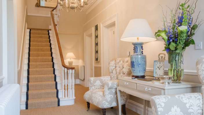 Eine blau-weiße Vase steht auf einem Tisch in einem Flur neben einer Treppe