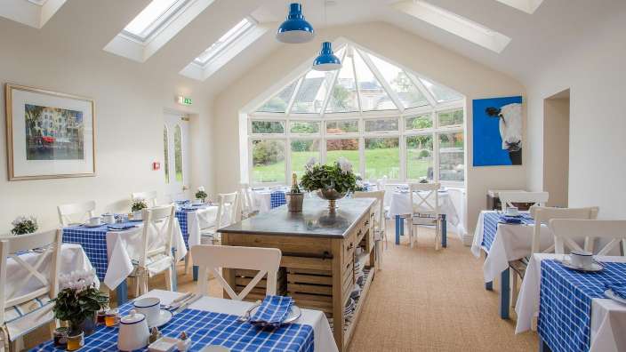 Ein Esszimmer mit blau karierten Tischdecken und weißen Stühlen