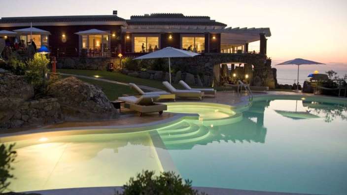 Ein großer Pool mit Liegestühlen und Sonnenschirmen in der Nähe eines großen Gebäudes