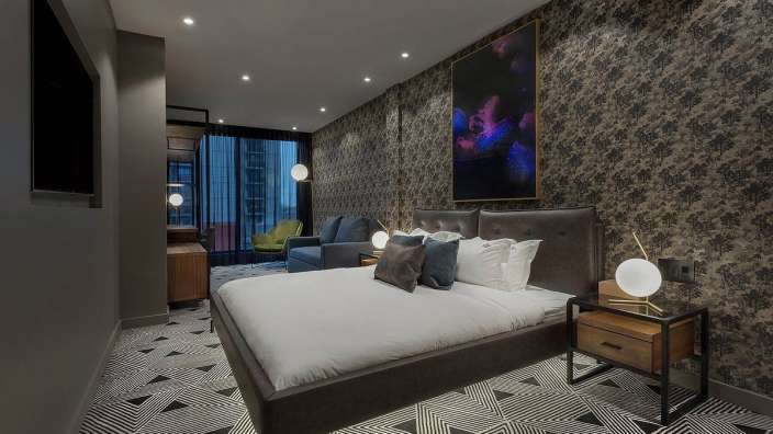 Ein Hotelzimmer mit einem großen Bett und einem Gemälde an der Wand