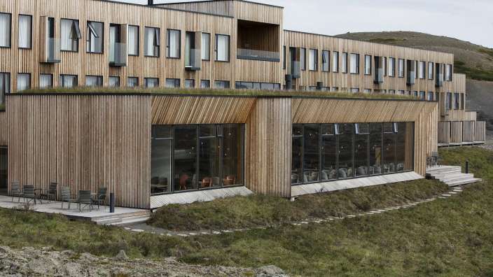 Ein Holzgebäude mit vielen Fenstern und einem grünen Dach