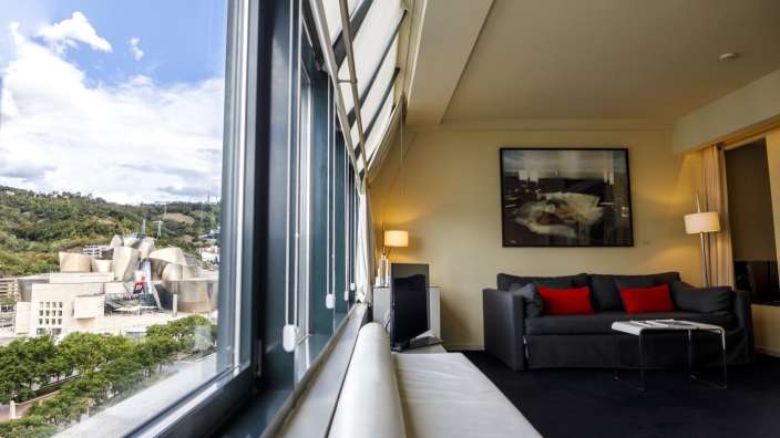 Ein Wohnzimmer mit einem großen Fenster und einem Bild an der Wand