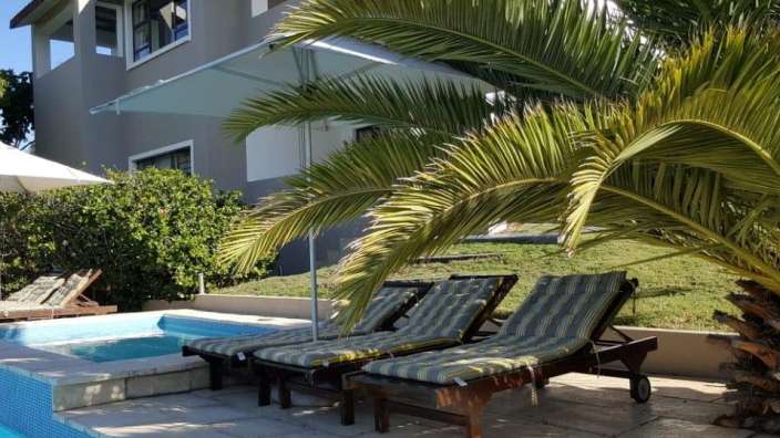 Liegestühle neben einem Swimmingpool mit einem Haus im Hintergrund