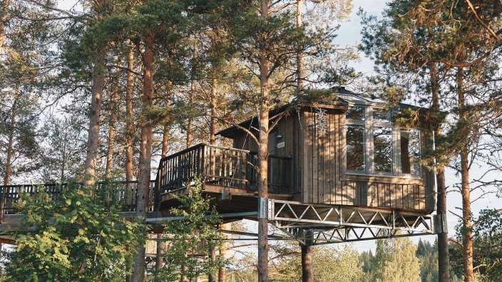 Ein Baumhaus inmitten eines Waldes mit einem Balkon