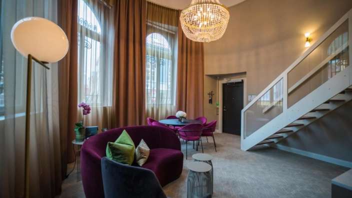 Ein Wohnzimmer mit lila Stühlen und einem Kronleuchter