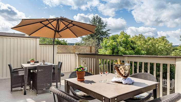 Eine Terrasse mit Tisch und Stühlen und einem Regenschirm