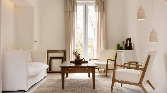 Ein Wohnzimmer mit weißen Möbeln und einem Holztisch