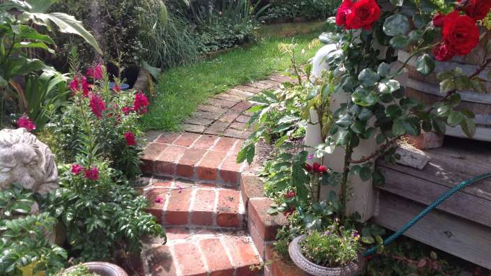 Ein Garten mit roten Rosen und einer Statue eines Löwen