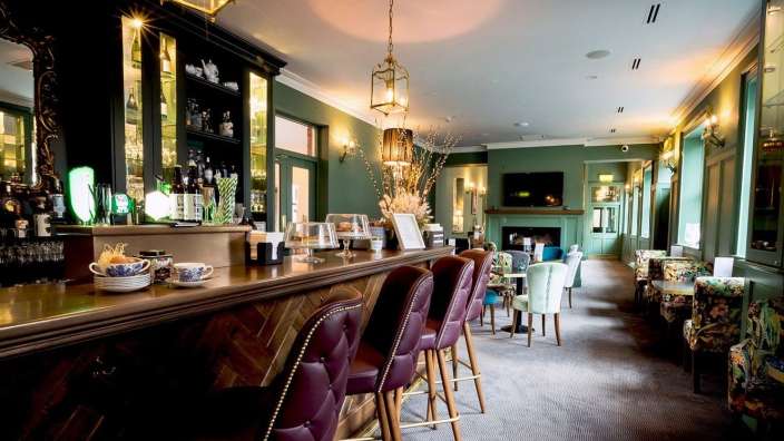 Eine lange Bar mit vielen Stühlen und Flaschen an der Theke