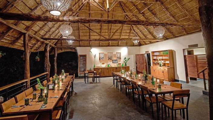 Eine lange Reihe von Tischen und Stühlen in einem Raum mit Strohdach