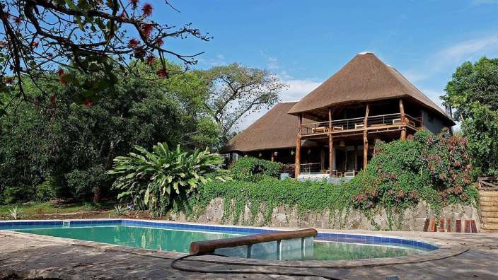 Ein großes Haus mit Strohdach und einem Pool davor