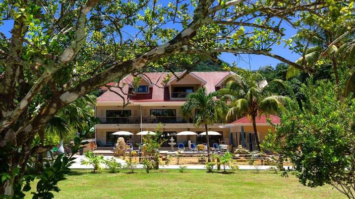 Ein großes Haus mit einem roten Dach und vielen Bäumen davor