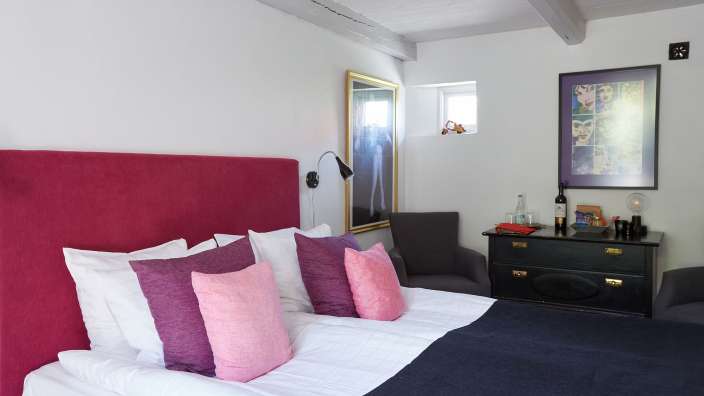 Ein Schlafzimmer mit einem roten Bettkopfteil und rosa Kissen