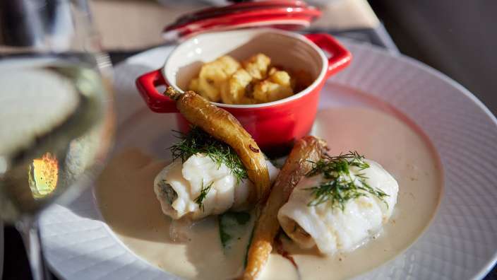 Ein weißer Teller mit einem roten Topf mit Kartoffelpuffern darauf