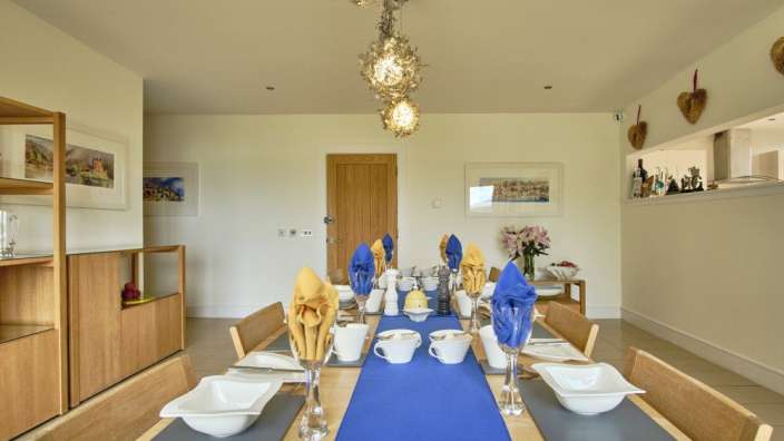 Ein Esszimmer mit einem blauen Tischläufer und weißen Tellern