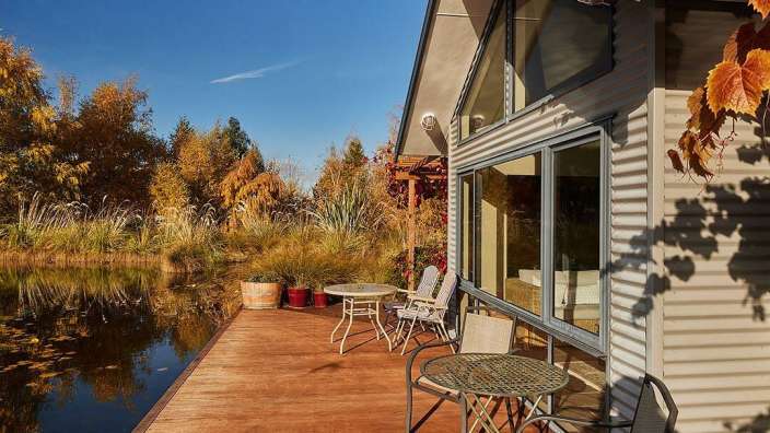 Ein Holzdeck mit einem Tisch und Stühlen neben einem Teich