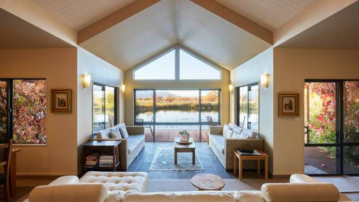 Ein Wohnzimmer mit vielen weißen Möbeln und einem großen Fenster mit Blick auf einen See