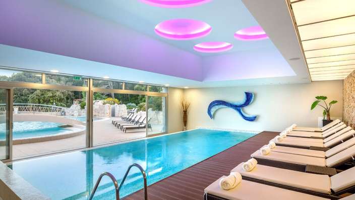 Ein großer Innenpool mit Liegestühlen und einem Gemälde an der Decke