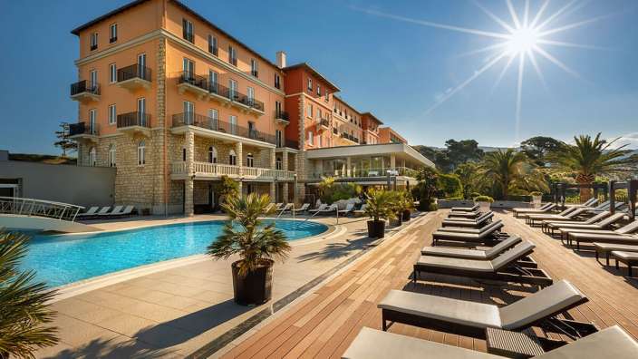 Ein großes Gebäude mit einem Pool und Liegestühlen davor