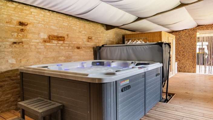 Ein grau-weißer Whirlpool steht auf einem Holzdeck