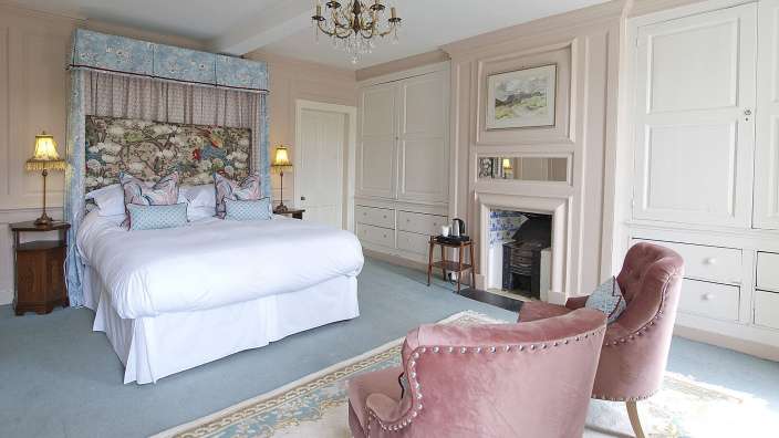 Ein Schlafzimmer mit einem Bett, einem Stuhl und einem Kamin