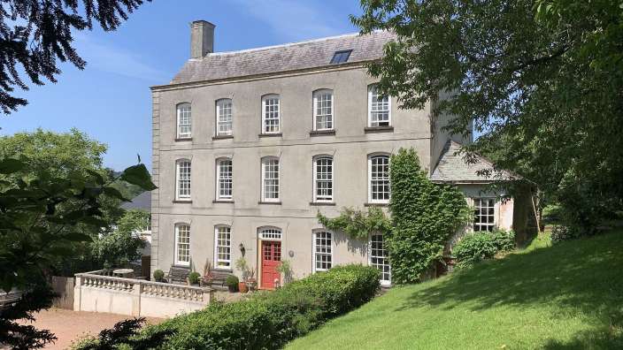 Ein großes Haus mit vielen Fenstern und einer roten Tür
