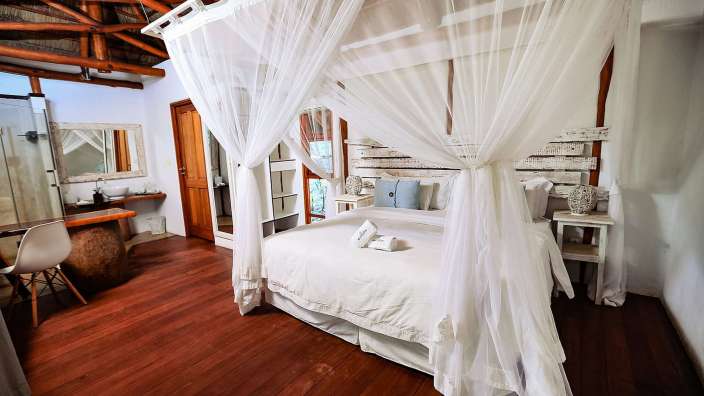 Ein Schlafzimmer mit einem Himmelbett und weißen Vorhängen