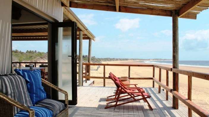 Eine Reihe von Stühlen steht auf einem Deck mit Blick auf den Strand