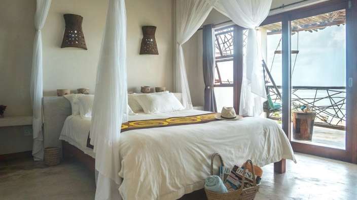 Ein Schlafzimmer mit Himmelbett und einem Korb mit Sandalen darauf