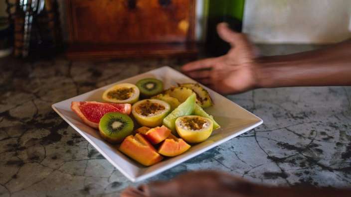 Eine Person greift nach einem Teller mit Früchten